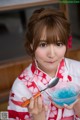 A woman in a kimono holding a bowl of blue liquid.