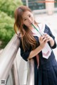 A woman in a school uniform drinking from a straw.