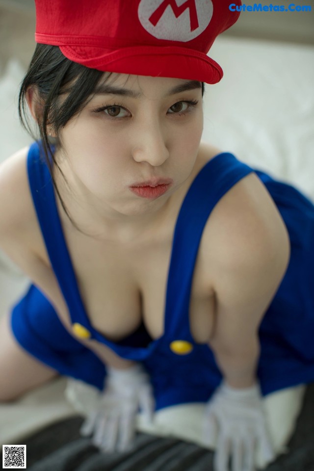 A woman in a red hat and blue overalls posing for a picture.
