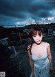 A woman standing on top of a roof under a cloudy sky.