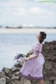 A woman in a purple dress holding a bunch of lavender.