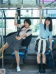 Two young women in school uniforms are sitting on a bus.