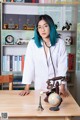 A woman with blue hair sitting at a desk with a stethoscope.