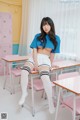 A woman sitting at a desk in a classroom.