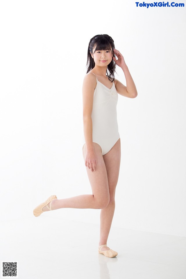 A young woman in a white leotard and pointe shoes.