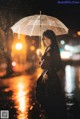 A woman standing in the rain holding an umbrella.