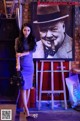 A woman standing in front of a picture of a man smoking a cigar.