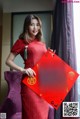 A woman in a red cheongsam holding a red envelope.